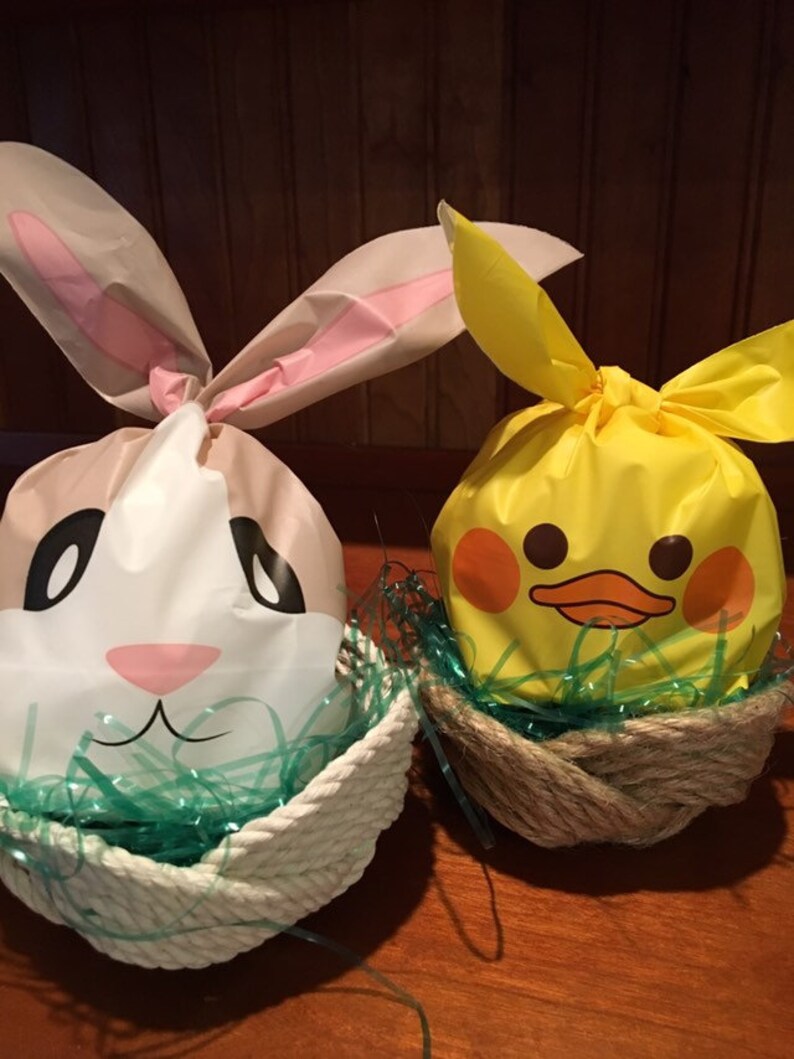 May include: Two Easter baskets filled with green grass and decorated with a bunny and a duck. The bunny basket is white with pink ears and a brown face. The duck basket is yellow with a black beak and eyes.