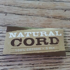 May include: A brown label with white text that reads "NATURAL CORD 100% COTTON &bull; 3 PLY".