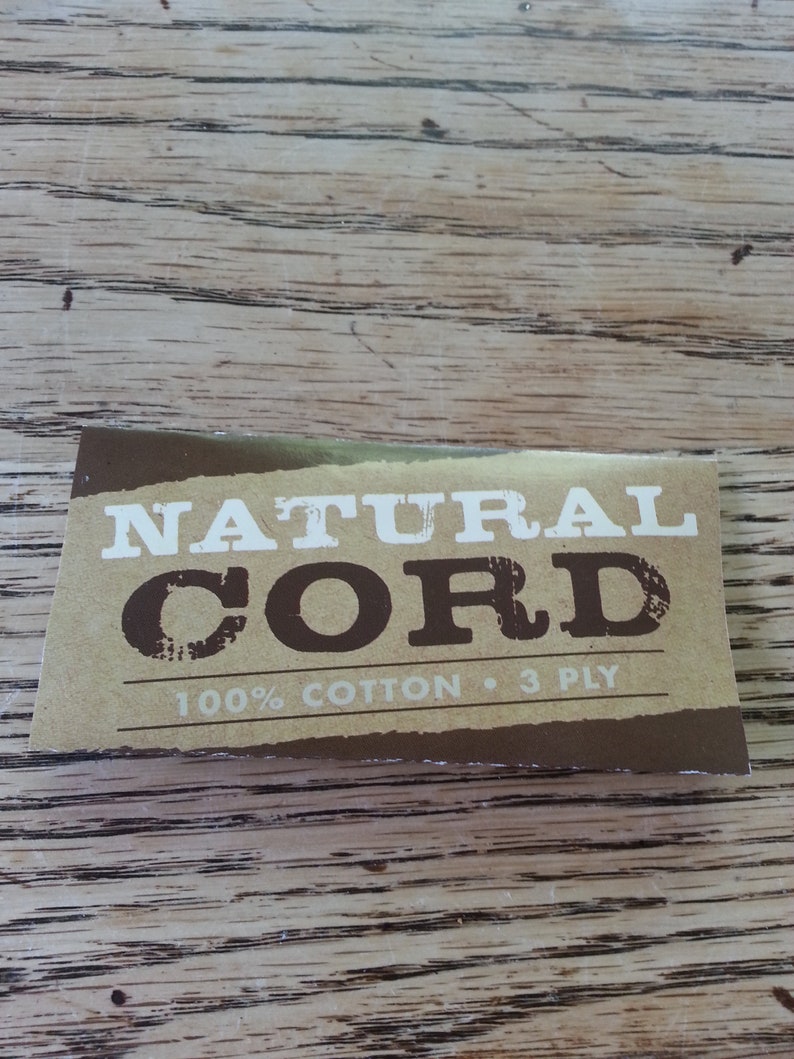 May include: A brown label with white text that reads "NATURAL CORD 100% COTTON &bull; 3 PLY".