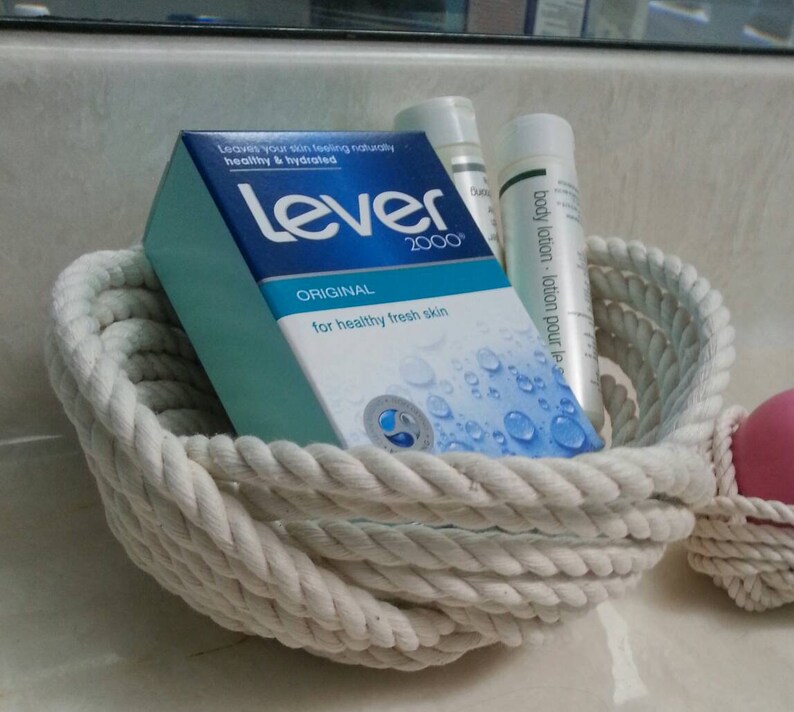 May include: A white rope basket filled with toiletries, including a bar of Lever 2000 soap, a bottle of body lotion, and a bottle of hand lotion.