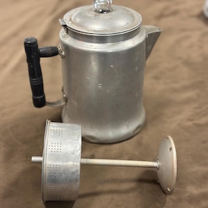 以下が含まれることがあります： 黒いハンドルと蓋の透明なガラスノブが付いた、ヴィンテージのアルミニウム製コーヒーパーコレーター。 フィルターは別です。 クラシックなキッチン家電です。