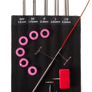 May include: A set of interchangeable knitting needles in a black case with pink and red accessories. The needles are labeled with sizes 000 (1.5 mm), 00 (1.75 mm), 0 (2.0 mm), 1 (2.25 mm), and 1.5 (2.5 mm).