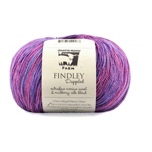 May include: A skein of Juniper Moon Farm Findley Dappled yarn in a purple, pink, and blue colourway. The label reads "extrafine merino wool & mulberry silk blend", "3.52oz (100g) 798yds (730m)", "AUS 1-3 (2.25-3.25mm) 127-32sts/4in", "US 8 (5.0mm) 21-32sts/4in", and "50% wool".