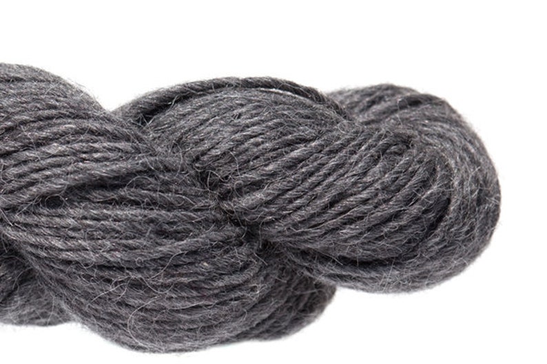 Puede incluir: Un ovillo de hilo gris oscuro, perfecto para tejer o hacer ganchillo.