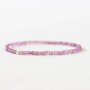 May include: A delicate bracelet featuring small, faceted pink gemstones strung together. The bracelet has a simple design with a silver-colored bead at the clasp. The gemstones are a soft, light pink color.