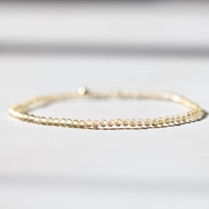 Puede incluir: Delicada pulsera con pequeñas cuentas redondas de color amarillo claro. Las cuentas están ensartadas para formar una banda fina y flexible. La pulsera tiene un brillo sutil y un diseño minimalista. Las cuentas están espaciadas uniformemente.