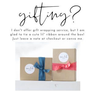 May include: Two gift boxes wrapped in brown paper, one with a blue ribbon and the other with a pink ribbon. Each box has a white sticker with the text "nom lab". The text "gifting?" is written at the top.