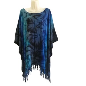 Peut inclure: Un poncho bleu et turquoise à motifs avec une bordure en franges. Le poncho est fait d'un tissu doux et léger et a une coupe ample.