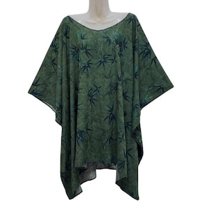 Puede incluir: Una túnica verde holgada con cuello redondo. La túnica está adornada con un estampado de hojas verde oscuro. La tela cae suelta, creando una silueta relajada. La prenda se exhibe en un maniquí.