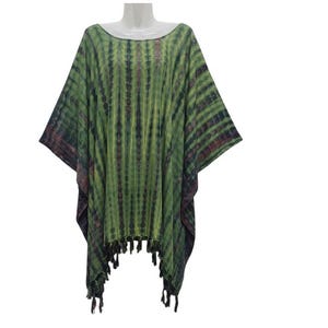 Puede incluir: Un poncho verde y negro teñido anudado con cuello redondo y ribete de flecos. El poncho se muestra en un maniquí y tiene un ajuste holgado y fluido. La tela tiene rayas verticales verdes y negras.