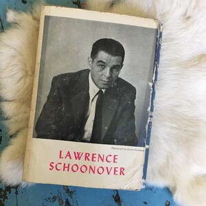 May include: A black and white photo of Lawrence Schoonover on the cover of a book. The book is titled "Lawrence Schoonover" and has a white background with black text. The photo was taken by Erich Hartmann.