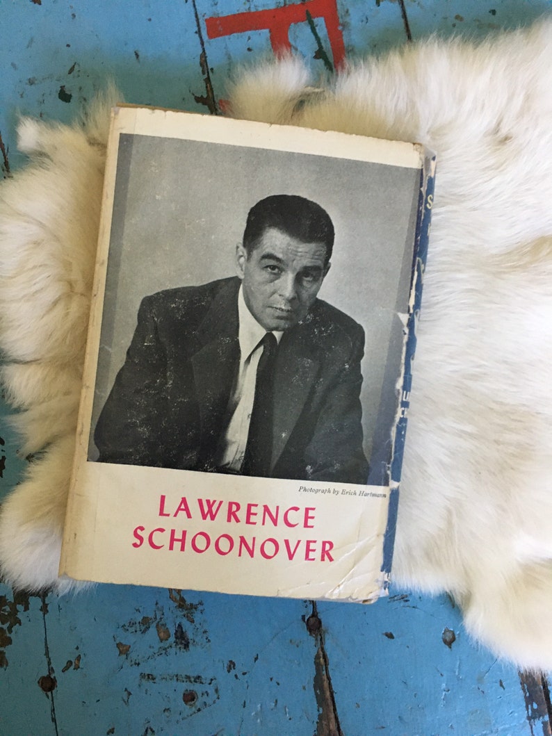 May include: A black and white photo of Lawrence Schoonover on the cover of a book. The book is titled "Lawrence Schoonover" and has a white background with black text. The photo was taken by Erich Hartmann.