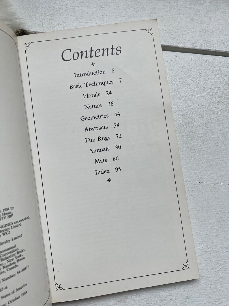 May include: A book titled "Contents" with a table of contents listing different rug designs, including florals, nature, geometrics, abstracts, fun rugs, animals, and mats. The book includes an introduction and index.