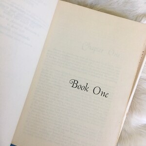 May include: An open book with the text "Chapter One" and "Book One" printed on the pages.