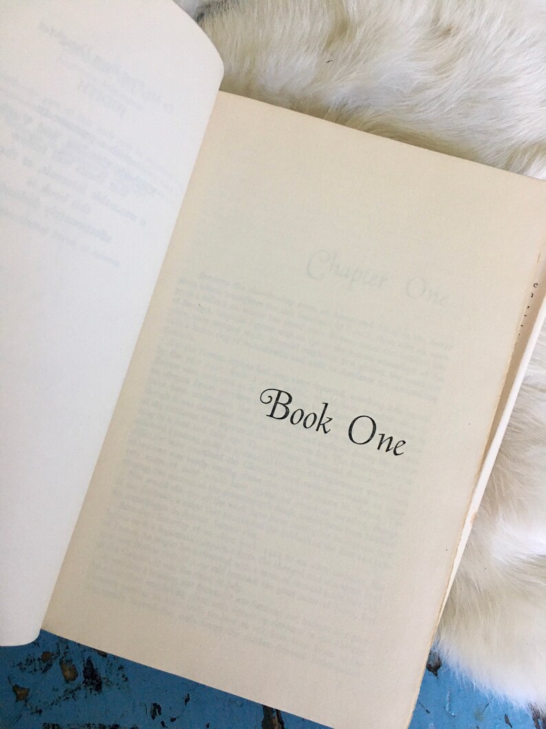 May include: An open book with the text "Chapter One" and "Book One" printed on the pages.
