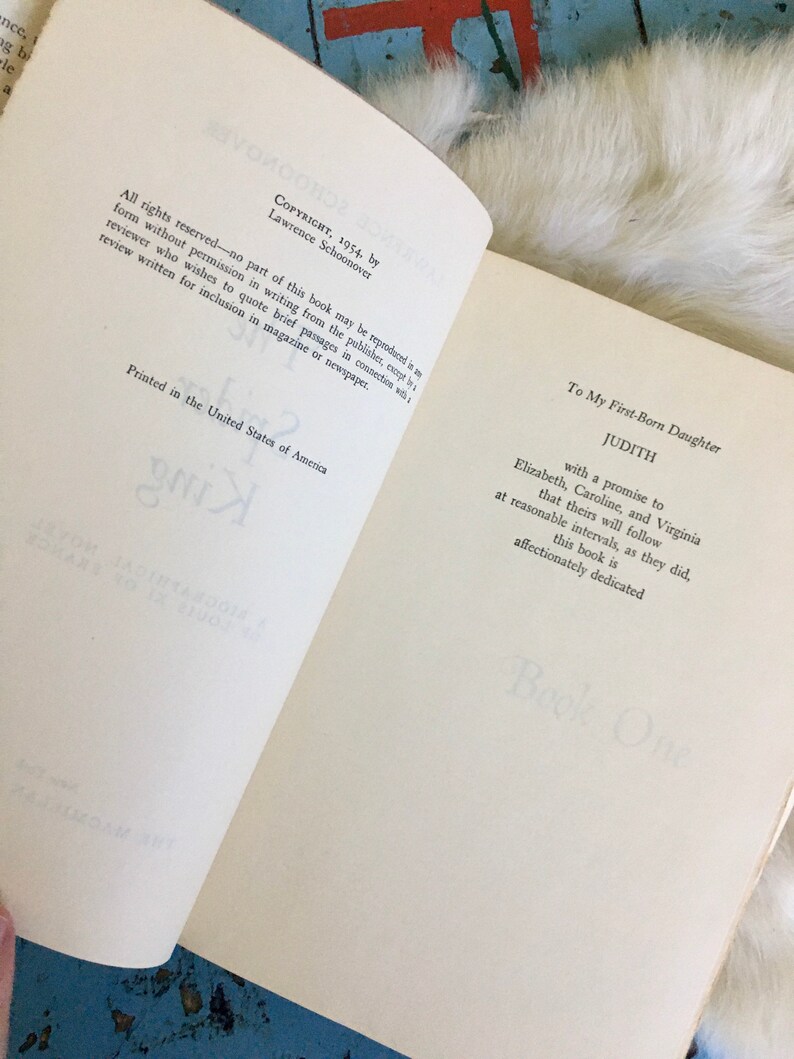 May include: A book titled "Judith" with the text "Copyright, 1954, by Lawrence Schoonover" and "Printed in the United States of America". The book is dedicated to the author's first-born daughter.
