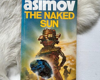 May include: Asimov's The Naked Sun science fiction novel cover featuring a colorful illustration of a large robot in a futuristic landscape.