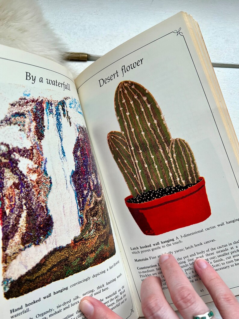 May include: A latch hook wall hanging depicting a cactus in a red pot. The cactus is green with brown stripes and is three-dimensional. The text "Desert flower" is at the top of the image.