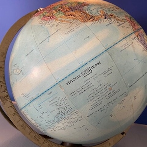 May include: A vintage blue and white globe with a brass stand. The globe is labeled "Replogle Globe" and includes information about international boundaries, state boundaries, other boundaries, and population.