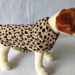 May include: A brown and black leopard print dog sweater with a white stuffed dog wearing it.