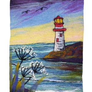 May include: A needle felted artwork depicting a white lighthouse with a red roof and a yellow light on a rocky shore. The lighthouse is surrounded by blue water with whitecaps and a purple and blue sky with white birds flying overhead. There are white flowers in the foreground.