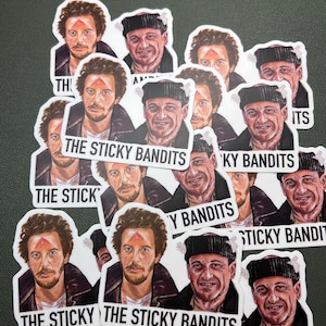 以下が含まれることがあります： 「The Sticky Bandits」という文字が印刷された、男性のグループが描かれた白いステッカー12枚セット。男性は冬服を着ており、額に赤い点があります。
