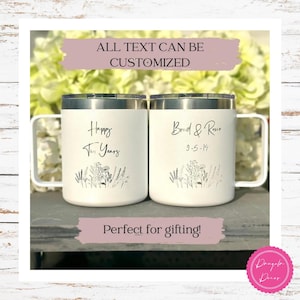 May include: Two white stainless steel tumblers with lids and handles. The left tumbler features the text "Happy Ten Years" and the right tumbler features "Brad & Roxie 9-5-14". Both have a black line art floral illustration at the base.