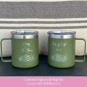 May include: Two olive green stainless steel mugs with clear lids and handles. The left mug is engraved with "Happy Ten Years" and a wildflower design. The right mug is engraved with "Bob & Kristen" and "9-6-19" above a matching wildflower design.