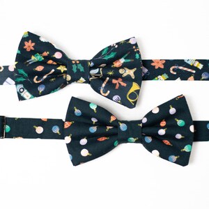Peut inclure: Deux nœuds papillon avec des sangles réglables. Le nœud papillon le plus grand a un fond bleu foncé avec un motif d'ornements de Noël, de cannes en sucre et d'autres décorations de Noël. Le nœud papillon le plus petit a un fond bleu foncé avec un motif d'ornements de Noël colorés.