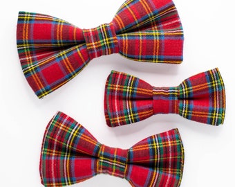 May include: Three red and green plaid bow ties of different sizes. The bow ties are arranged in a row from largest to smallest.
