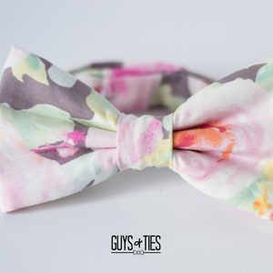 May include: A bow tie with a floral pattern in shades of pink, yellow, and green. The bow tie is made of a soft, lightweight fabric and has a subtle sheen.