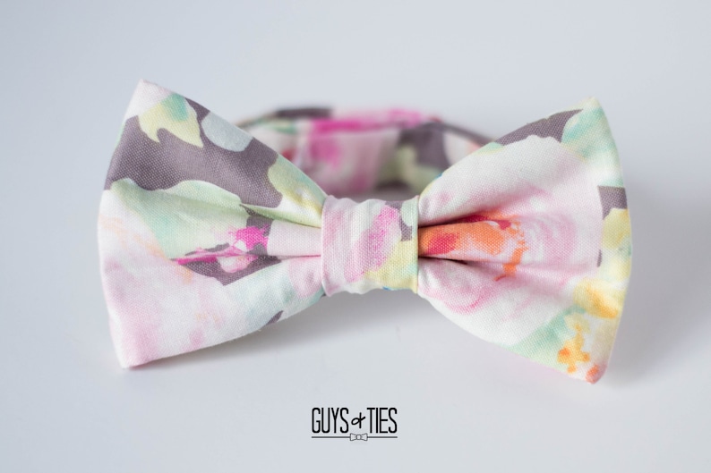 May include: A bow tie with a floral pattern in shades of pink, yellow, and green. The bow tie is made of a soft, lightweight fabric and has a subtle sheen.