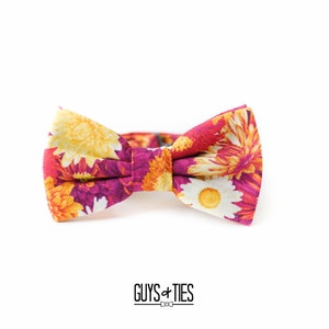 May include: A floral bow tie with a pink background and yellow, orange, and white flowers.