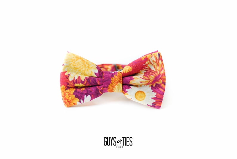 May include: A floral bow tie with a pink background and yellow, orange, and white flowers.