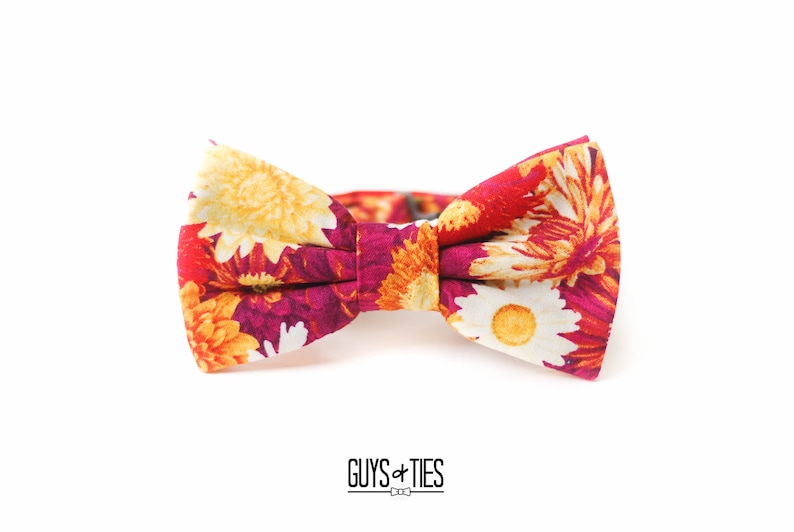 May include: A floral bow tie with a red, white, and yellow pattern. The bow tie is made of fabric and has a classic bow shape.
