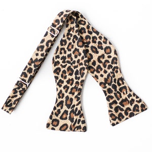 May include: A brown and black leopard print bow tie with an adjustable strap.