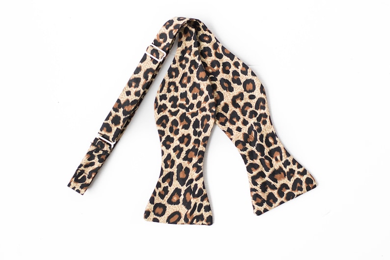 May include: A brown and black leopard print bow tie with an adjustable strap.