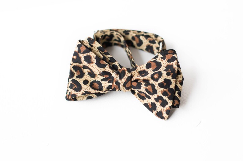 May include: A brown and tan bow tie with a leopard print pattern.