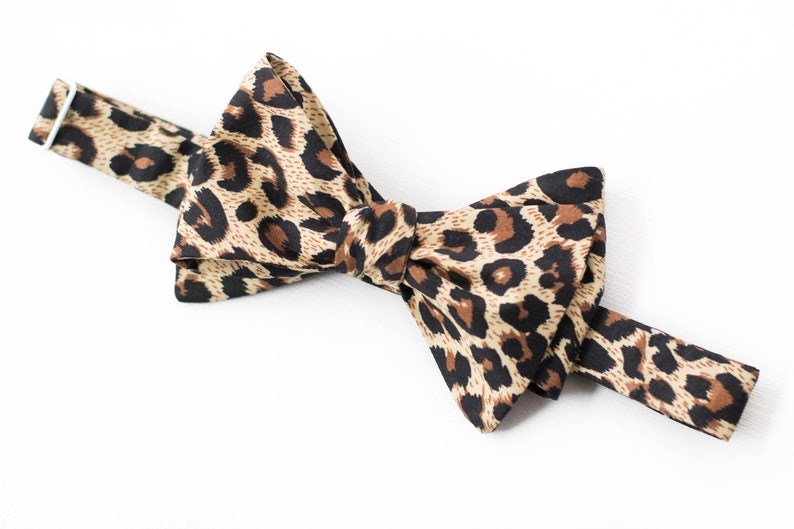 May include: A brown and black bow tie with a leopard print pattern.