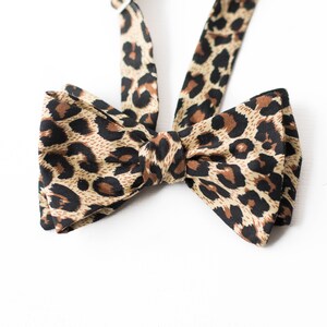 May include: A brown and black leopard print bow tie.