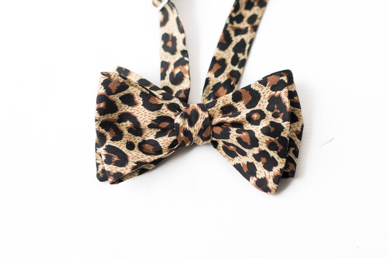 May include: A brown and black leopard print bow tie.