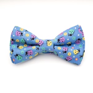 May include: A blue bow tie with a pattern of colourful ladybugs and white polka dots.