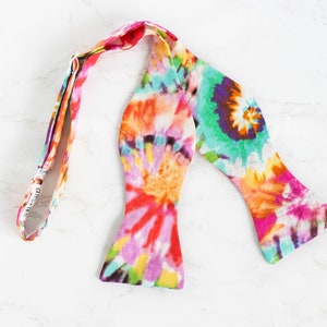Può includere: Un papillon tie-dye colorato con un motivo rosa, arancione, giallo, verde e blu brillante.