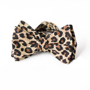 May include: A brown and black bow tie with a leopard print pattern.
