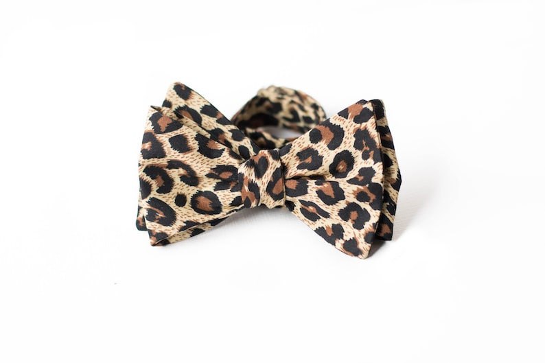 May include: A brown and black bow tie with a leopard print pattern.