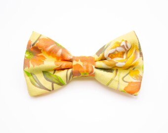 May include: A yellow bow tie with a floral pattern in shades of orange and green.