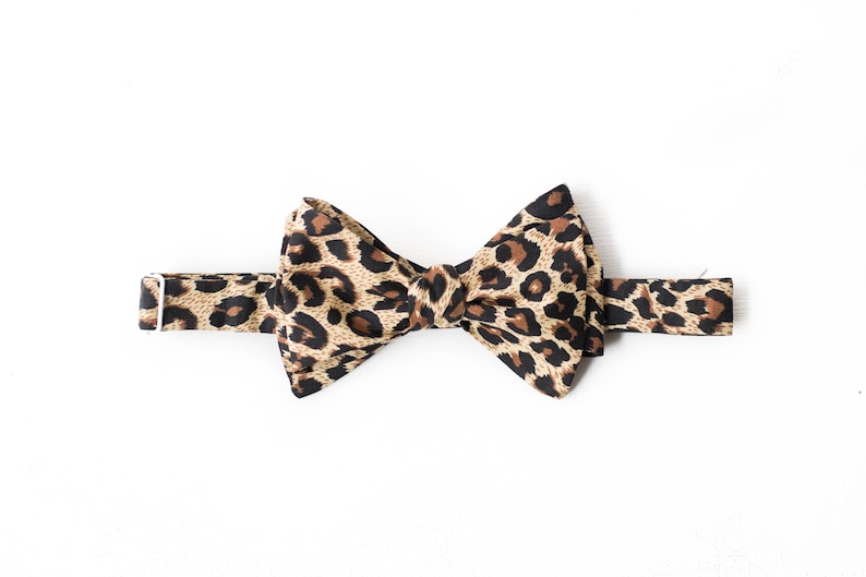 May include: A brown and black bow tie with a leopard print pattern.