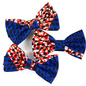 May include: Three bow ties in blue, red, and white patterned fabric. The bow ties are made of a soft, comfortable material and are perfect for adding a touch of style to any outfit.