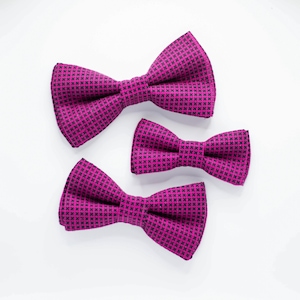 May include: Three pink bow ties with a black and white geometric pattern. The bow ties are arranged in a decreasing size order from left to right.