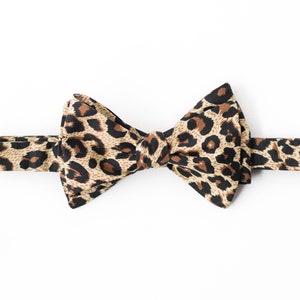 May include: A brown and black bow tie with a leopard print pattern.